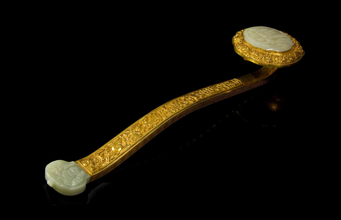 A Gilt Bronze and Jade Inset Ruyi Scepter, Length 18: A Gilt Bronze and Jade Inset Ruyi Scepter, the standard having raised decoration of the bajixiang, the celadon jade plaques relief carved with flowers and lingzhi. Length 18 1/8 inches.