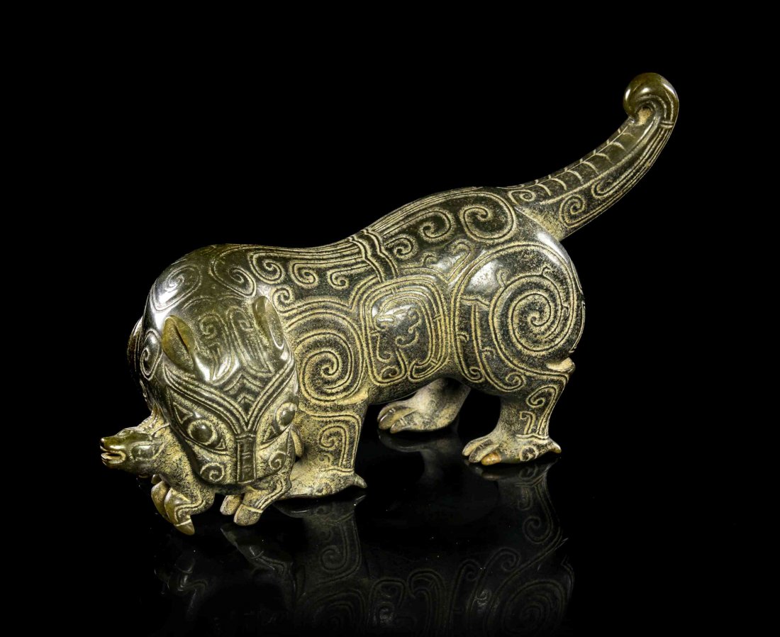 A Carved Jade Figure of a Tiger, Width 9 1/2 inches.: A Carved Jade Figure of a Tiger, Eastern Zhou/Han Dynasty, the beast depicted four square with prey in its jaws, its tail extended behind, having incised scrollwork throughout. Width 9 1/2 inches. Pro