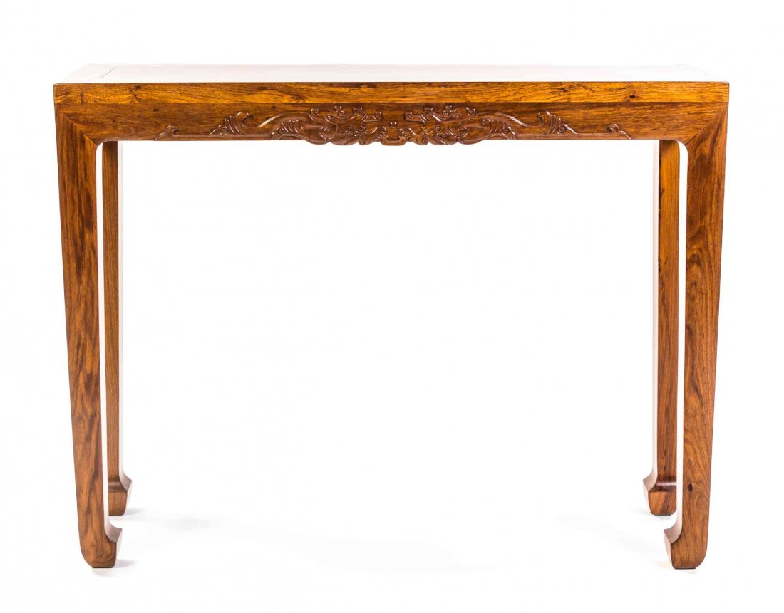 A Narrow Huanghuali Corner-Leg Table, Height 33 x width: A Narrow Huanghuali Corner-Leg Table, having a plank top without waist or cornice, the relief carved apron with confronting dragons pursuing a central pearl, raised on block legs ending in elephant fe