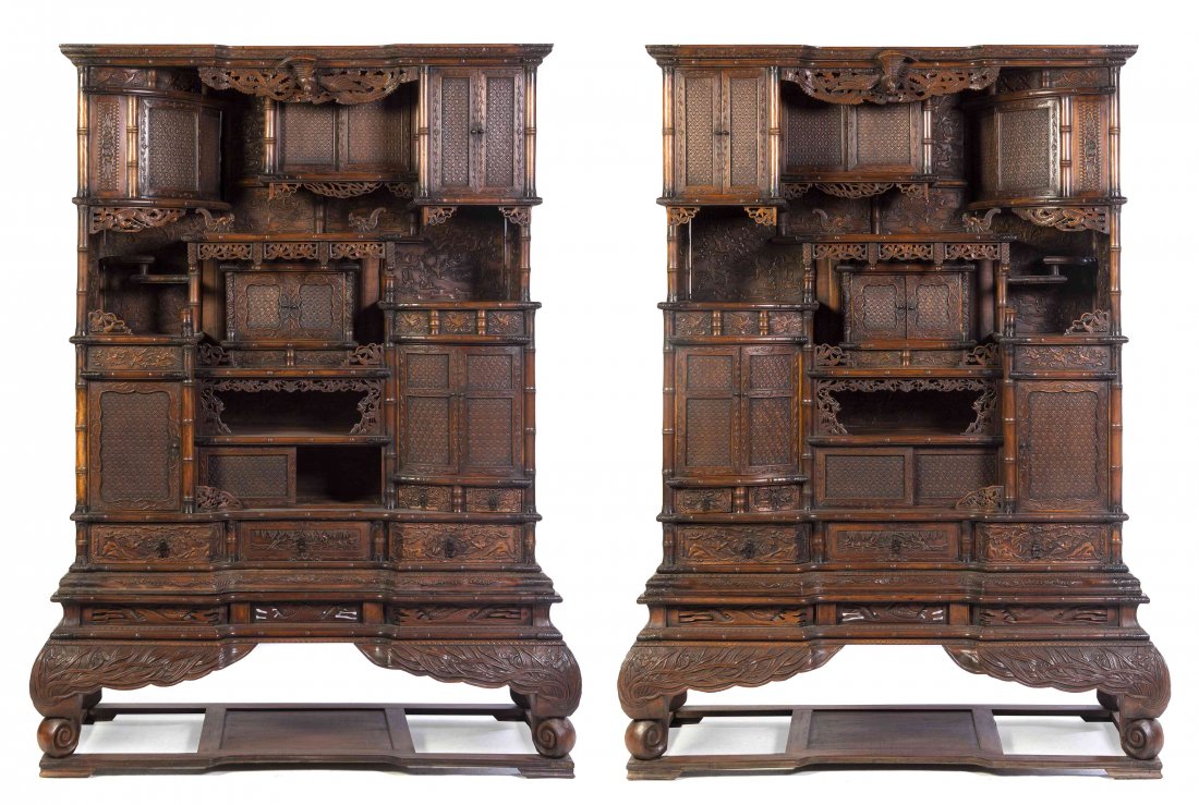 A Pair of Carved Hardwood Display Cabinets, Height 83 x: A Pair of Carved Hardwood Display Cabinets, each having a molded cornice with a recessed center above tiers of shelves and cabinet doors of varying sizes, with relief carving throughout depicting vary