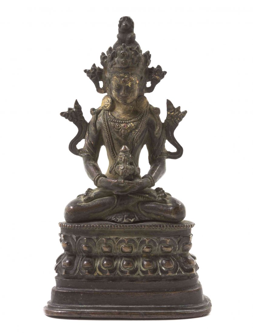 A Tibetan Gilt Bronze Figure of a Buddhist Deity,: A Tibetan Gilt Bronze Figure of a Buddhist Deity, 19th century, the figure depicted seated with crown and jewelry, the hands clasped in front and bearing a reliquary, mounted on a waisted double lotus