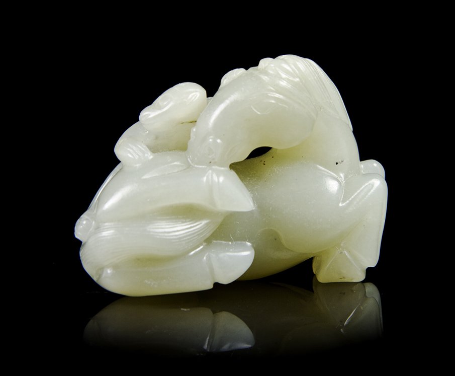 A Carved Celadon Jade Toggle of a Horse and Monkey,: A Carved Celadon Jade Toggle of a Horse and Monkey, of an even pale celadon hue, the horse depicted recumbent, its neck craned around the monkey on its back. Width 2 1/4 inches.