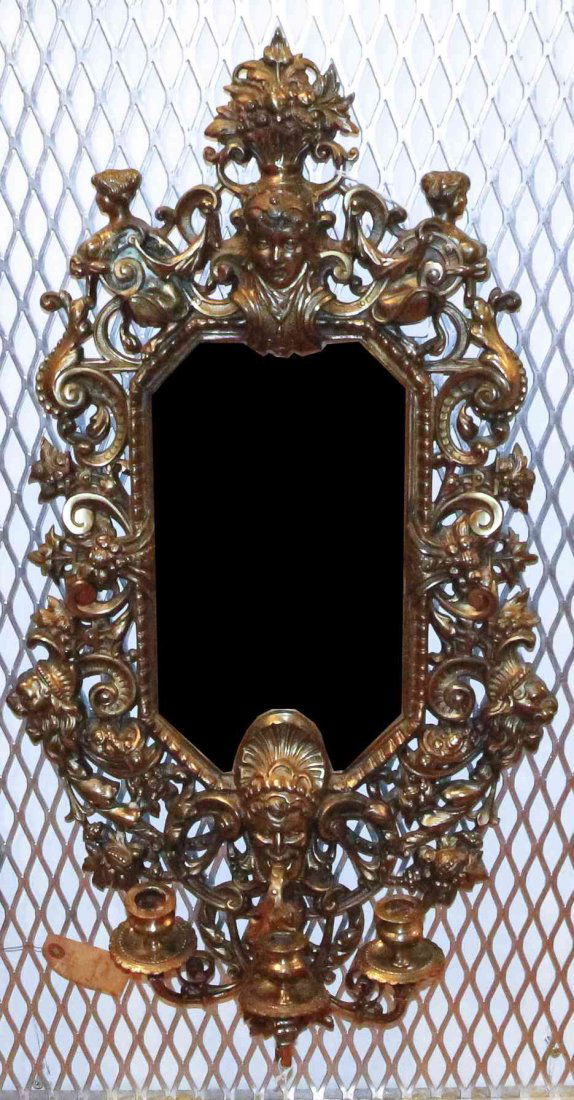 A Rococo Style Gilt Metal Mirror, Height 28 1/2 x width: A Rococo Style Gilt Metal Mirror, having a flowering urn form crest over the octagonal plate with allover mask decoration, the base fitted with a three scrolling candle arms. Height 28 1/2 x width 15