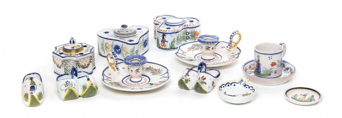 Eleven Quimper Faience Table Articles, Height of first: Eleven Quimper Faience Table Articles, comprising two inkwells, two chambersticks, two pairs of clogs, a single clog, a butter, a spoon tray and a cup and saucer, together with an associated faience i