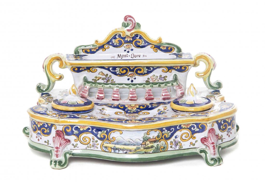 A Continental Faience Inkstand, Width 11 1/4 inches.: A Continental Faience Inkstand, likely French, of shaped form having two cylindrical covered inkwells flanking a central molded well, surmounted by a pen rest that reads "Mont-Dore," painted throughou
