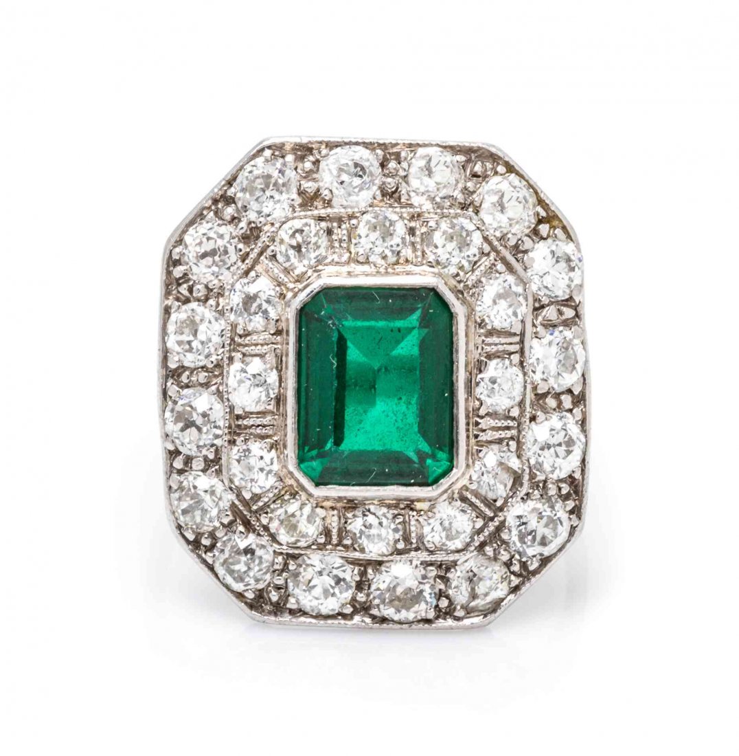 An Art Deco Platinum, Diamond and Simulated Emerald: An Art Deco Platinum, Diamond and Simulated Emerald Ring, in a millegrain edged octagonal setting with engraved shoulders, containing one octagonal step cut garnet and glass doublet measuring approxim