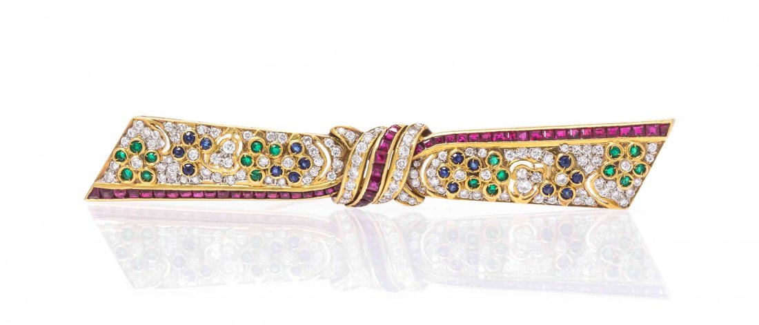 An 18 Karat Gold, Diamond, Ruby, Sapphire and Emerald: An 18 Karat Gold, Diamond, Ruby, Sapphire and Emerald Bar Brooch, in a stylized knotted ribbon motif, containing numerous round brilliant cut diamonds weighing approximately 1.00 carat total, numerous