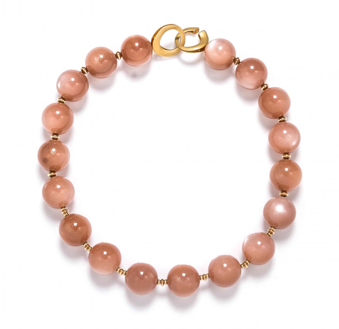 A Single Strand Moonstone Bead Necklace,: A Single Strand Moonstone Bead Necklace, consisting of 18 "peach" moonstone beads measuring approximately 20.00 mm in diameter strung alternating with gold tone spacer beads and a gold tone clasp. Pro