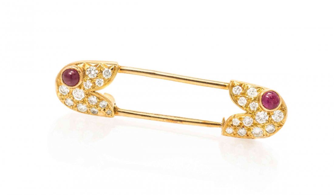 An 18 Karat Yellow Gold, Diamond and Ruby Safety Pin: An 18 Karat Yellow Gold, Diamond and Ruby Safety Pin Brooch, Van Cleef & Arpels, France, Circa 1977, containing 24 round brilliant cut diamonds and two round cabochon cut rubies. Stamp: VCA 77 750 117
