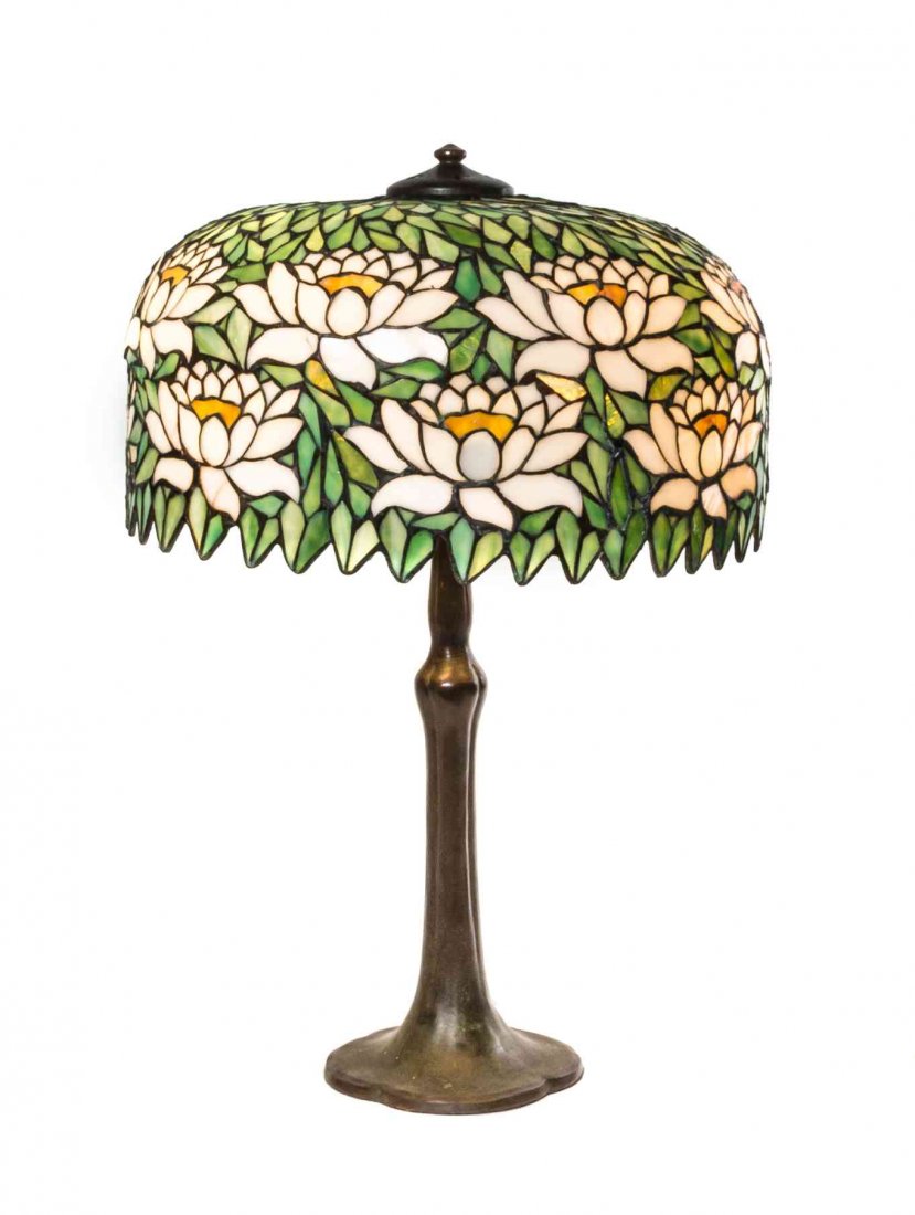 An American Leaded Glass and Bronze Table Lamp,: An American Leaded Glass and Bronze Table Lamp, having a domed shade with lotus blossoms on a green ground, raised on a bronze base with a circular foot. Diameter of shade 18 1/2 x height overall 27 1