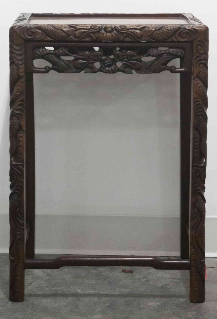 A Chinese Carved Hardwood Side Table, Height 24 x width: A Chinese Carved Hardwood Side Table, depicting writhing dragons pursuing the flaming pearl, together with a Chinese ceramic umbrella stand, raised on a wood base. Height 24 x width 17 x depth 12 1/2 