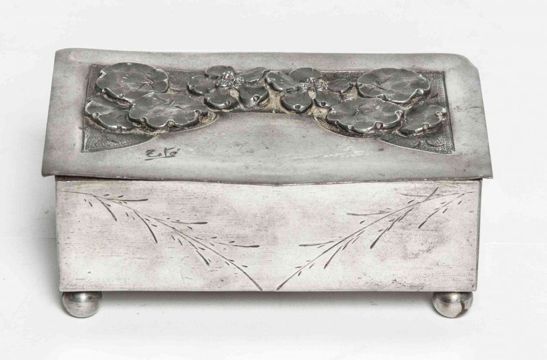A French Art Deco Pewter Music Box, the design by: A French Art Deco Pewter Music Box, the design by Romain de Tirtoff Erte (Russian, 1892-1990), the hinged lid modeled with flowers in relief and signed Erte, raised on spherical feet, the base stamped