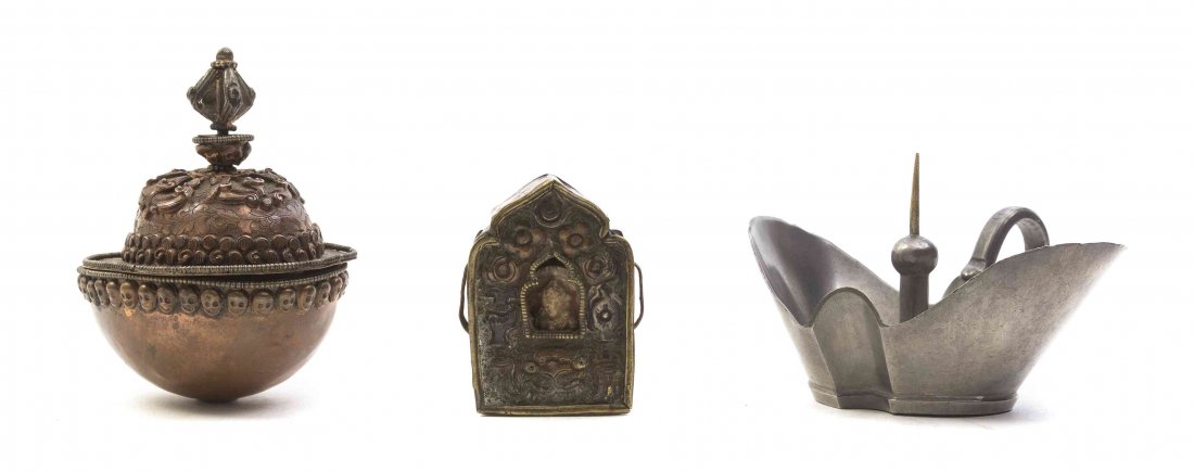 A Tibetan Small Metal Gau, Height of first 2 5/16: A Tibetan Small Metal Gau, of typical form containing a stone carved figure of a bodhisattva, together with a Tibetan copper covered bowl encircled with skulls and an ingot form silver pricket stick.