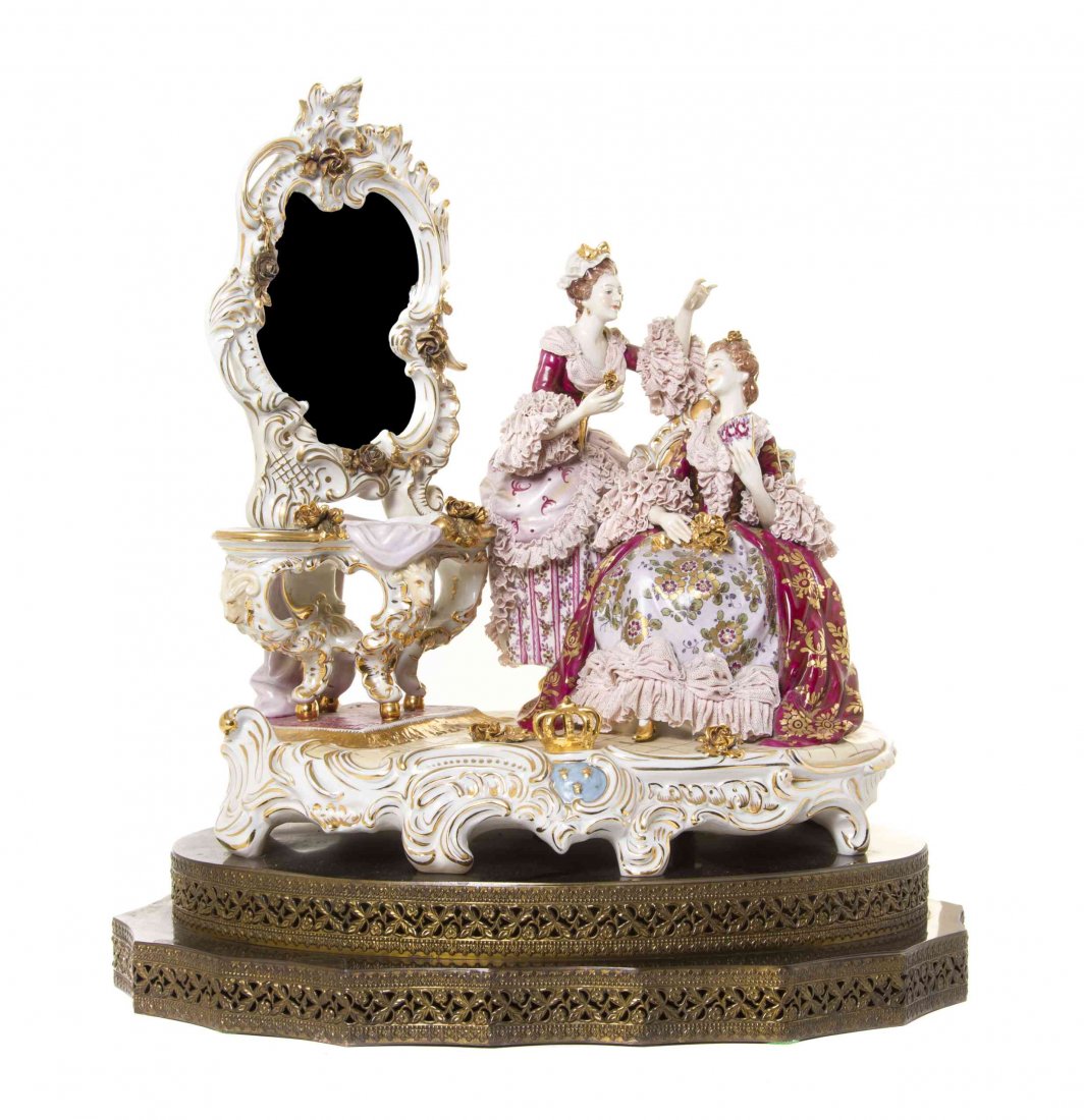 A Continental Porcelain Figural Group, Width 16 1/2: A Continental Porcelain Figural Group, depicting two ladies with wearing dresses with lace trim next to a dressing table and mirror, raised on a stepped gilt metal base. Width 16 1/2 inches. Property 