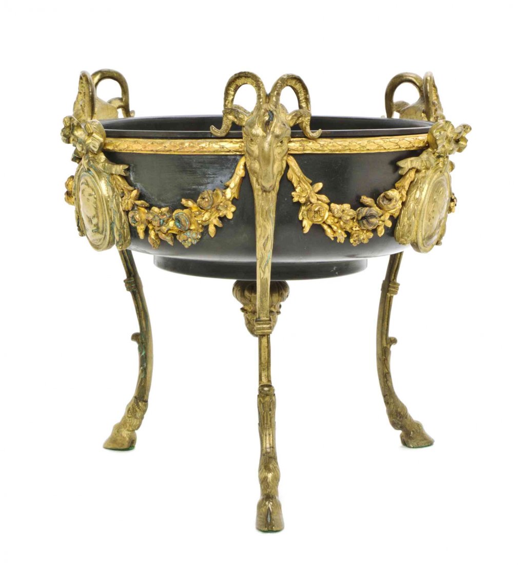 A Neoclassical Gilt Bronze Center Bowl, Height 9 1/4: A Neoclassical Gilt Bronze Center Bowl, having a circular tole liner, set in a stand cast with ribbon-tied profile medallions and floral garlands, raised on three supports headed by ram masks and endi