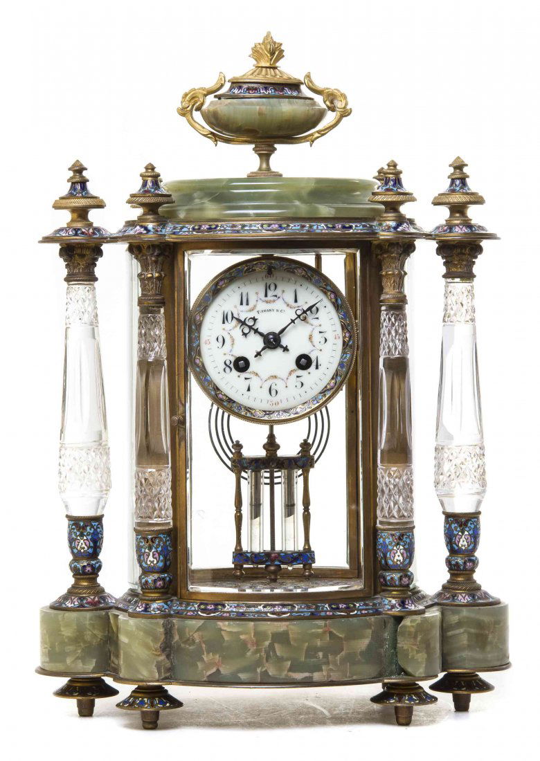 A French Onyx, Gilt Bronze, Cut Glass and Champleve: A French Onyx, Gilt Bronze, Cut Glass and Champleve Mantel Clock, RETAILED BY TIFFANY & CO., having a circular enameled dial with Arabic numerals, the case surmounted by a flaming urn finial over glaz