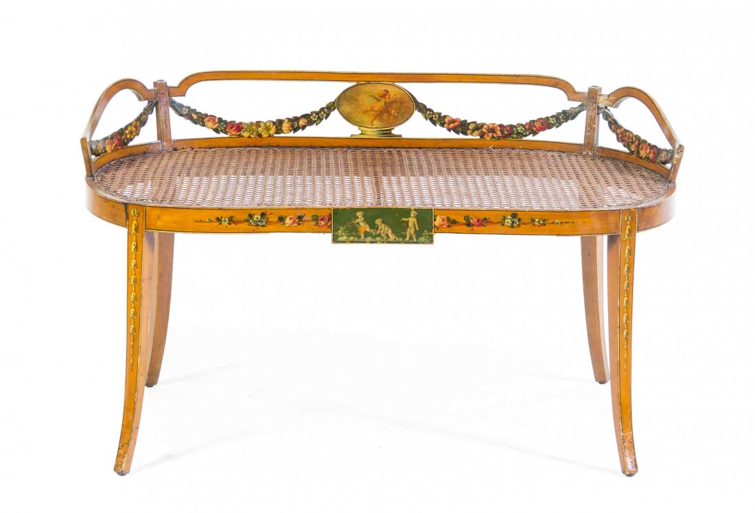 An Edwardian Satinwood Window Bench, Height 22 1/2 x: An Edwardian Satinwood Window Bench, with a caned seat, low open backrest and slightly flared legs, painted with cherub plaques and foliate swags. Height 22 1/2 x width 36 x depth 13 3/4 inches. Prope