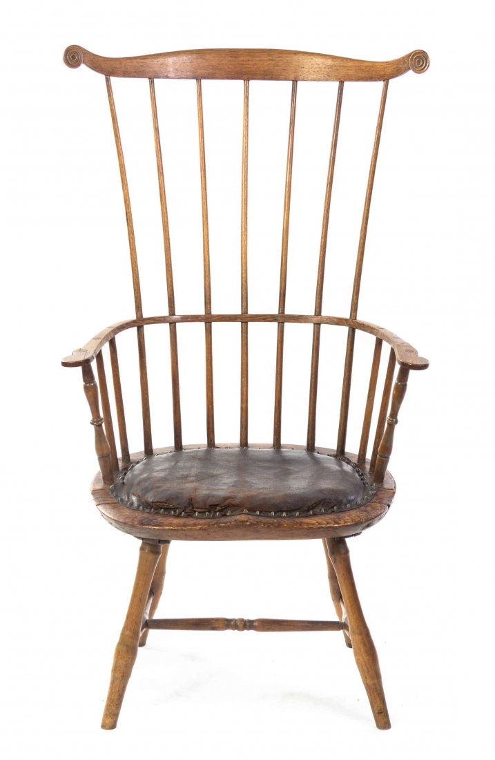 An American Oak Windsor Comb-Back Chair, Height 45: An American Oak Windsor Comb-Back Chair, having a rosette-carved crest rail above a spindle back and shaped arms over a studded leather seat, raised on turned legs joined by an H-form stretcher. Heigh
