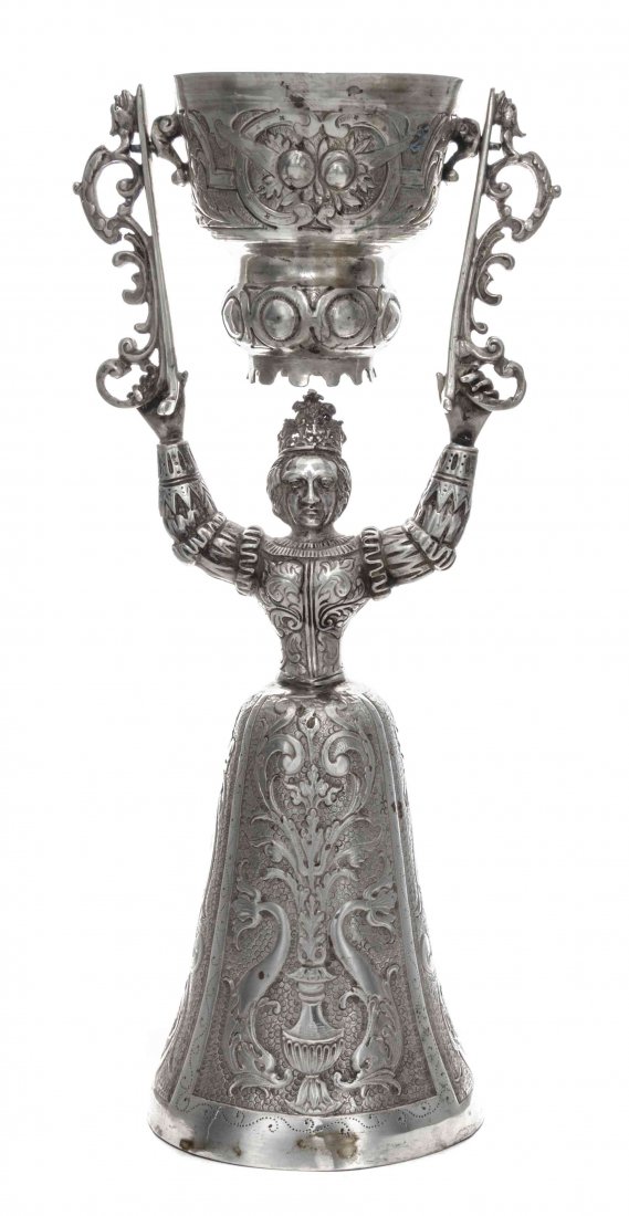 A German Silver Wager Cup, Height 10 1/2 inches.: A German Silver Wager Cup, Probably B. Neresheimer & Sohne, Hanau, Late 19th Century, in 17th century style, formed as a woman holding a swiveling cup above her head, her skirts chased with dolphins a
