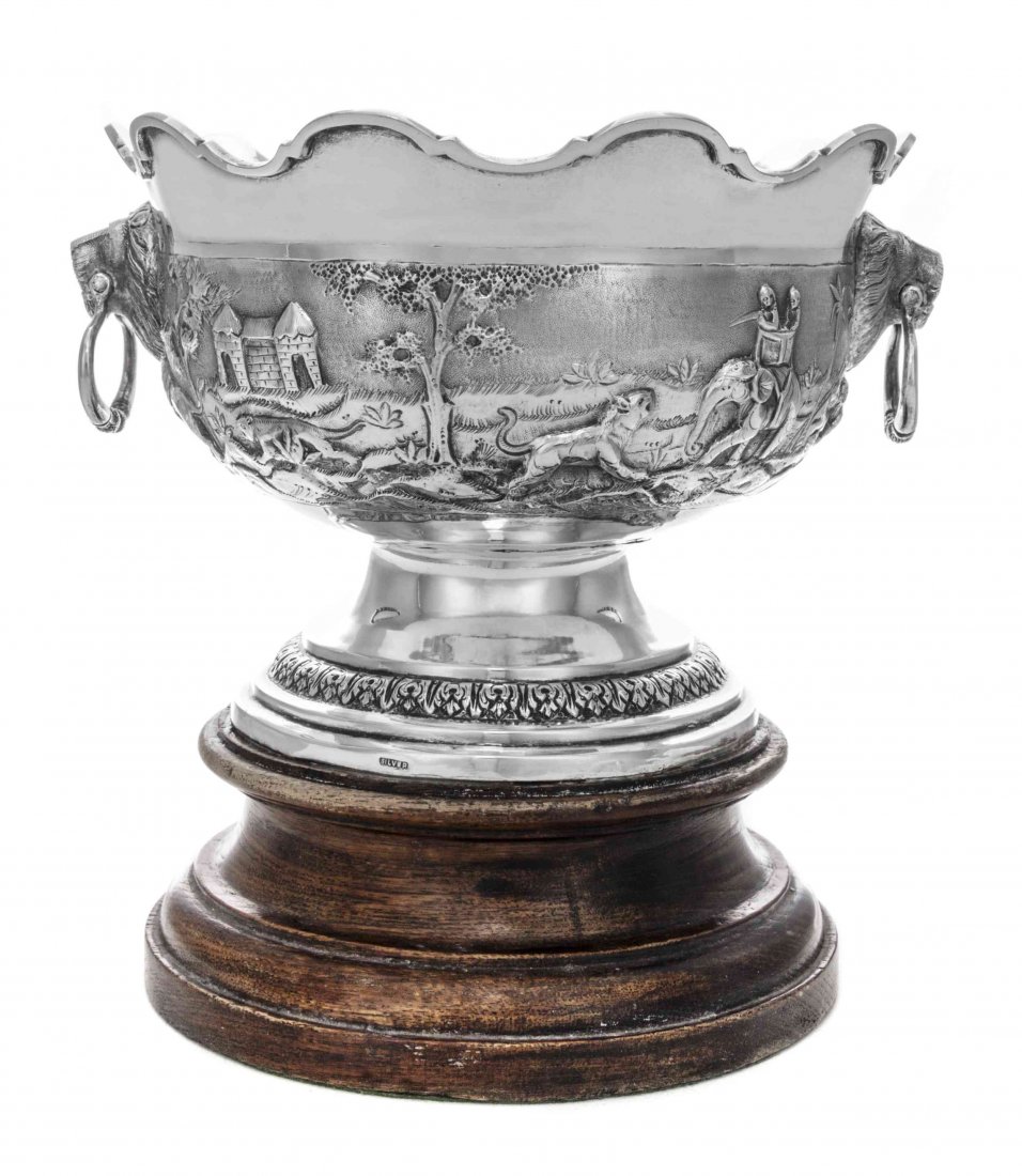 An Indian Silver Small Monteith Bowl, Height overall 8: An Indian Silver Small Monteith Bowl, Late 19th Century, of typical form with notched rim, the sides embossed and chased with jungle and hunting scenes including elephants and lions, the ends with rin