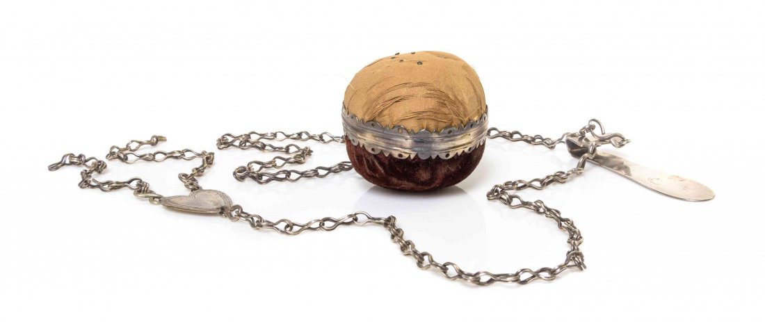 A Silver-Mounted Velvet Pin Cushion, Length overall 18: A Silver-Mounted Velvet Pin Cushion, 19TH CENTURY, suspended from a chain connected to a belt clip with an illegible signature, with a heart shaped plaque monogrammed A. Length overall 18 1/4 inches.