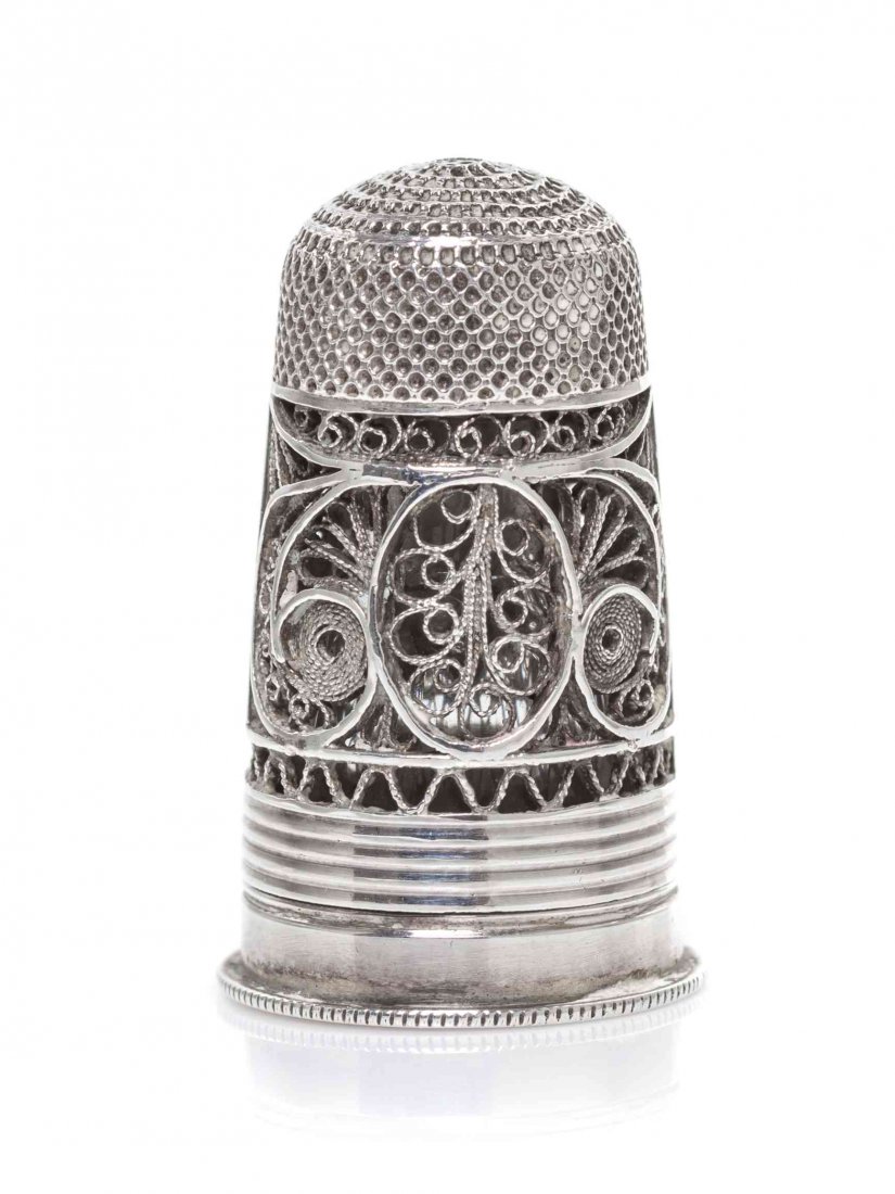 A Regency Silver Filigree Combination Thimble, Height 1: A Regency Silver Filigree Combination Thimble, EARLY 19TH CENTURY, the thimble with a wide band of scrolling filigree and applied with a vacant oval reserve, the screw-off base mounted with a cut glas
