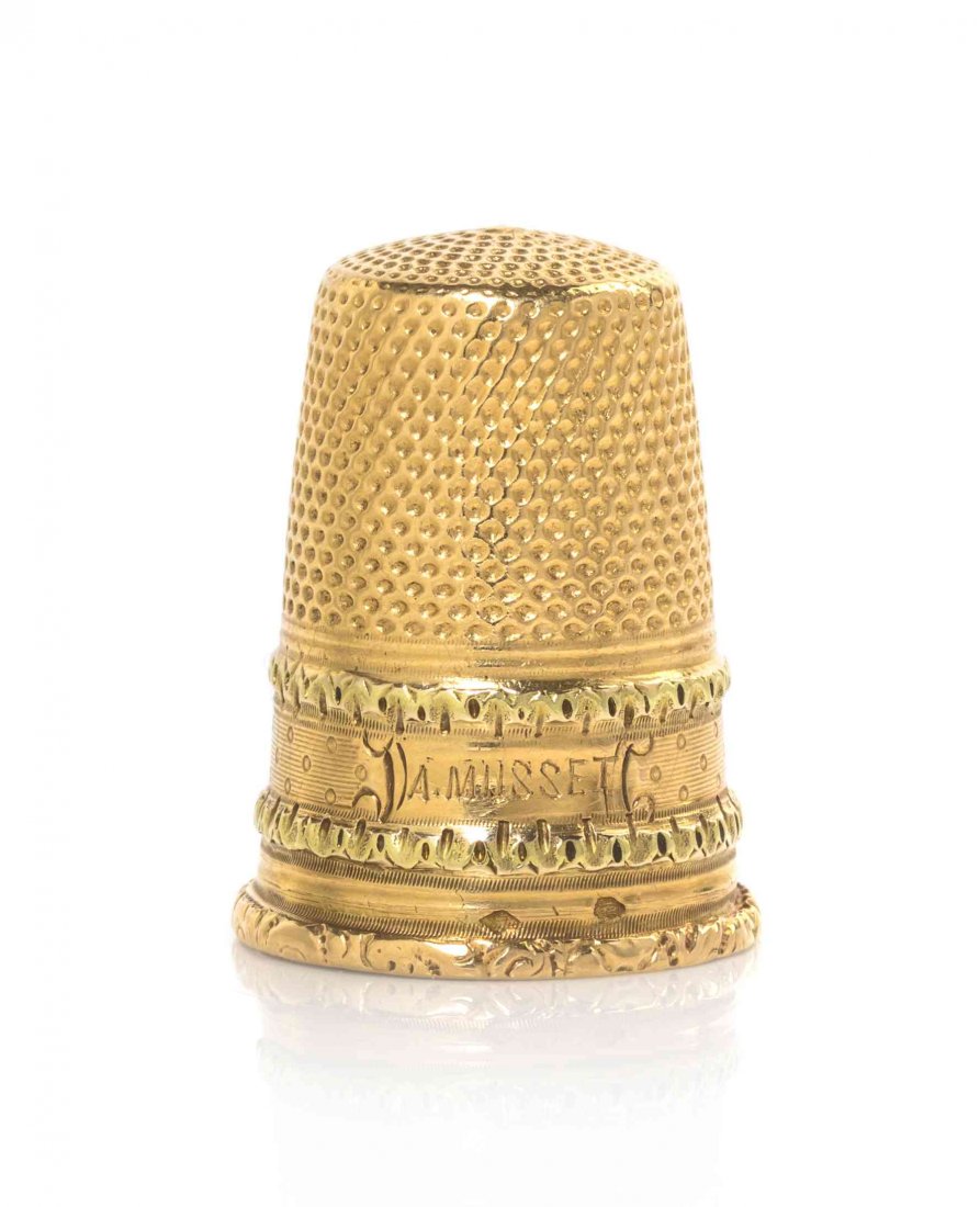 A French Gold Thimble, Height 1 inch.: A French Gold Thimble, 2ND HALF 19TH CENTURY, engraved with bosses against a reeded ground between applied foliate bands and a strapwork cartouche enclosing the name "A MUSSET;" marked near rim with m
