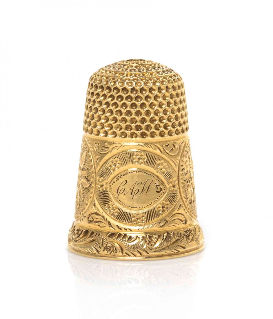 An American Gold Thimble, Height 7/8 inch.: An American Gold Thimble, 19TH CENTURY, the lower body with a wide engraved and bright-cut band having linked roundels enclosing flower heads and monogram CAW, the rim engraved with running foliage, s