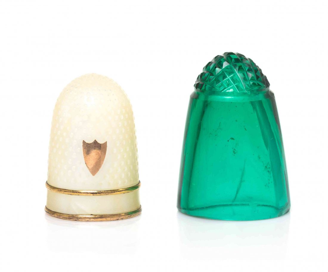 A French Mother-of-Pearl Thimble, Height of first 7/8: A French Mother-of-Pearl Thimble, LIKELY EARLY 19TH CENTURY, having a gilt shield-form cartouche over two gilt metal bands, together with a Bohemian green glass example. Height of first 7/8 inch.