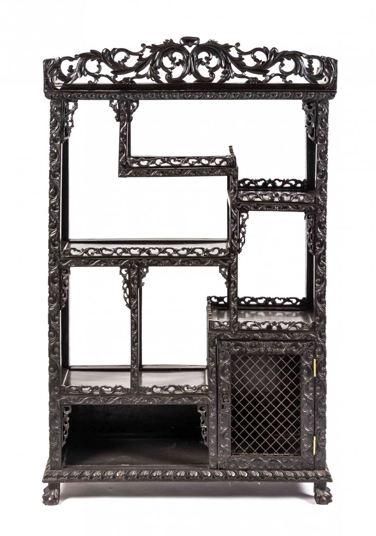 A Chinese Export Hardwood Etagere, Height 60 x width 37: A Chinese Export Hardwood Etagere, the pierce carved cornice depicting scrolled, leafy vines above the open cascading tiers of shelves with pierced galleries, having a mesh door cabinet to the lower r