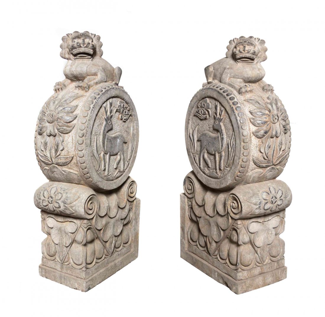 A Pair of Chinese Carved Stone Architectural Elements,: A Pair of Chinese Carved Stone Architectural Elements, each depicting a Buddhistic lion, recumbent atop a drum form and capital form standard, with a stag and ruyi clouds in relief, with floral elemen