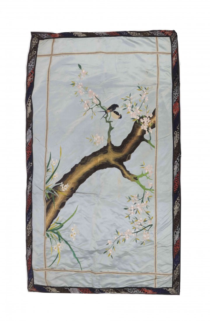 A Chinese Embroidered Silk Panel, Height 66 x width 34: A Chinese Embroidered Silk Panel, 20TH CENTURY depicting a pair of swallows amongst flowering prunus branches on a sky blue ground, within embroidered borders depicting Buddhist emblems. Height 66 x w