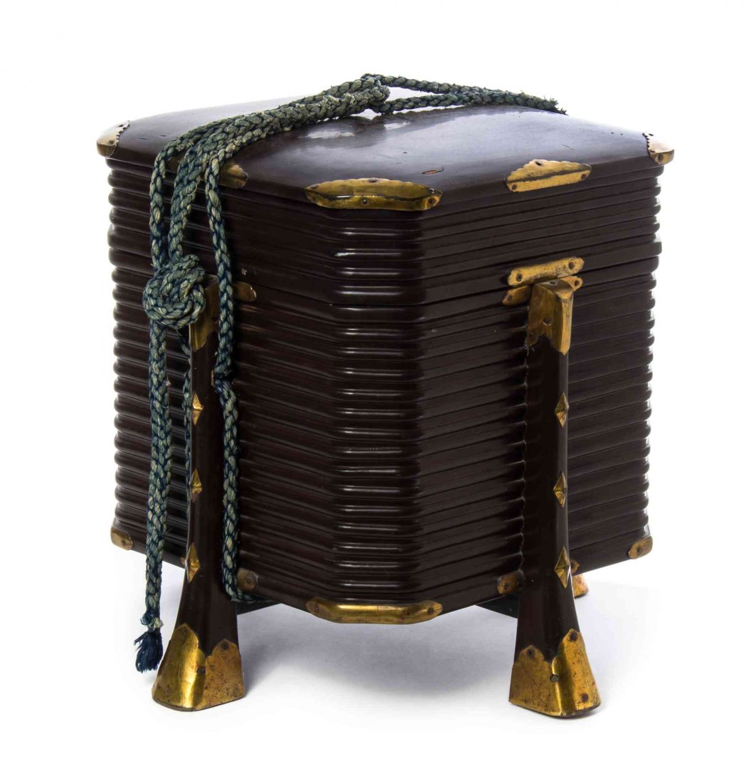 A Japanese Lacquer Shell Game or Kai-Oke Box, Height 15: A Japanese Lacquer Shell Game or Kai-Oke Box, of squared form having horizontal ribs, with gilt metal mounts and tied cord decoration. Height 15 inches.