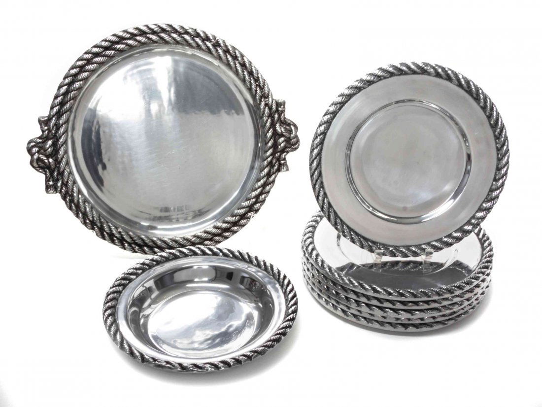 A Betty Barrena Aluminum Dinnerware Set, Width of: A Betty Barrena Aluminum Dinnerware Set, comprising 24 underlay plates with gadrooned borders, 2 serving trays with sectioned bowls, 2 rectangular trays, 1 circular bowl, 3 circular serving trays, 1 o