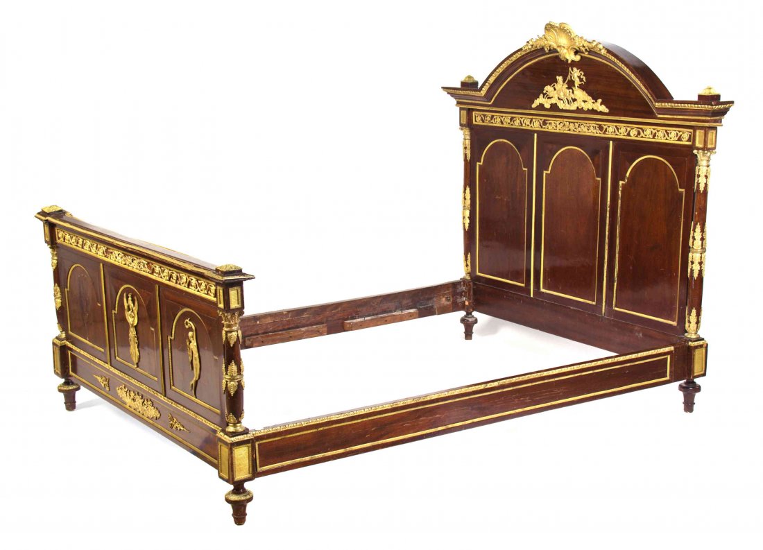 An Empire Style Gilt Bronze Mounted Mahogany Bed, FIRST: An Empire Style Gilt Bronze Mounted Mahogany Bed, FIRST HALF 20TH CENTURY, having domed headboard with foliate and figural mounts, the headboard and footboard each flanked by turned columns. Height of