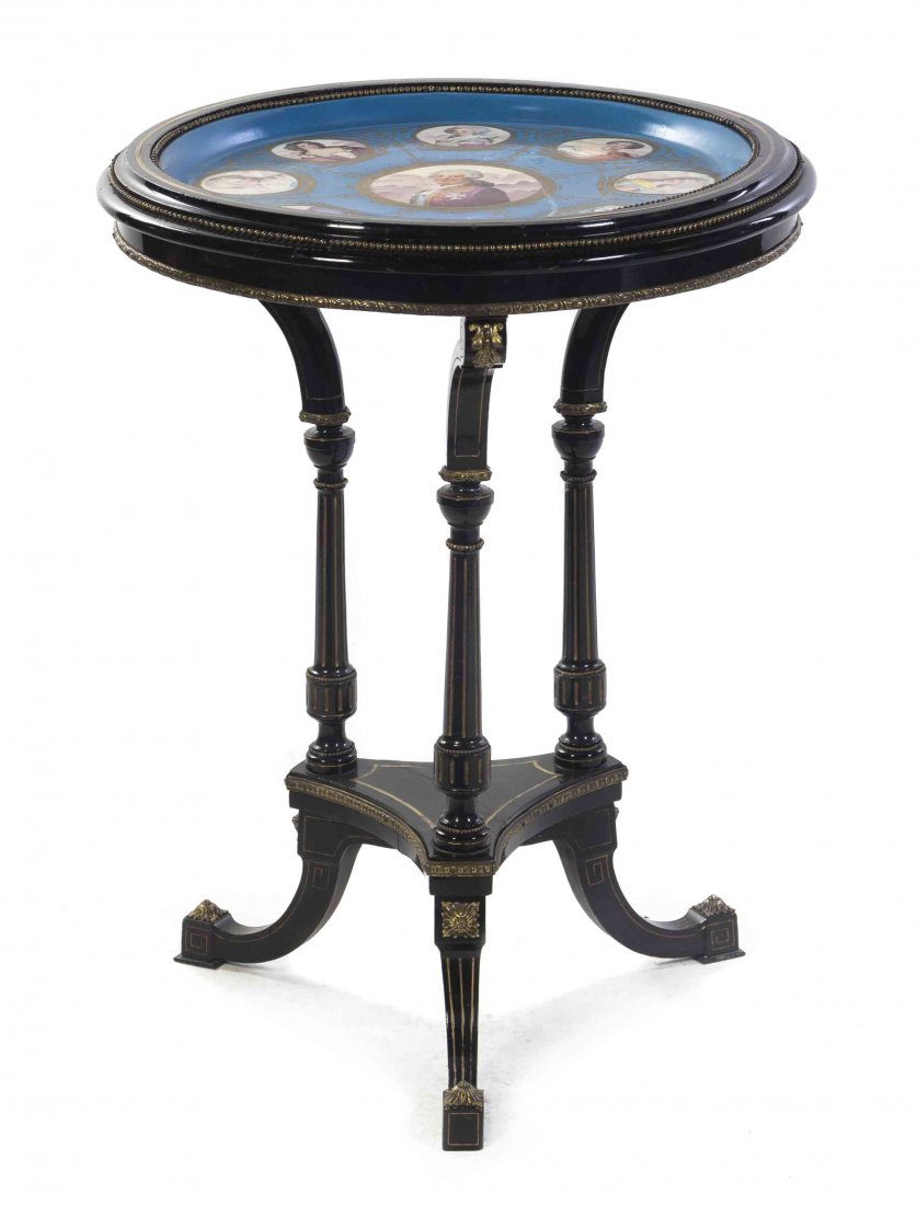 A Napoleon III Sevres Style Porcelain Inset Ebonized: A Napoleon III Sevres Style Porcelain Inset Ebonized Gueridon, the circular top depicting Louis XVI and members of his court on a gilt highlighted bleu celeste ground, raised on three supports joined 