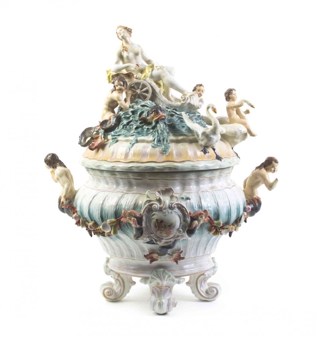 A Capodimonte Porcelain Punch Bowl and Cover, Width: A Capodimonte Porcelain Punch Bowl and Cover, the cover modeled as a maiden riding a chariot upon waves with Triton, a young merman, dolphins and a putto astride a swan below, the bowl having mermen h