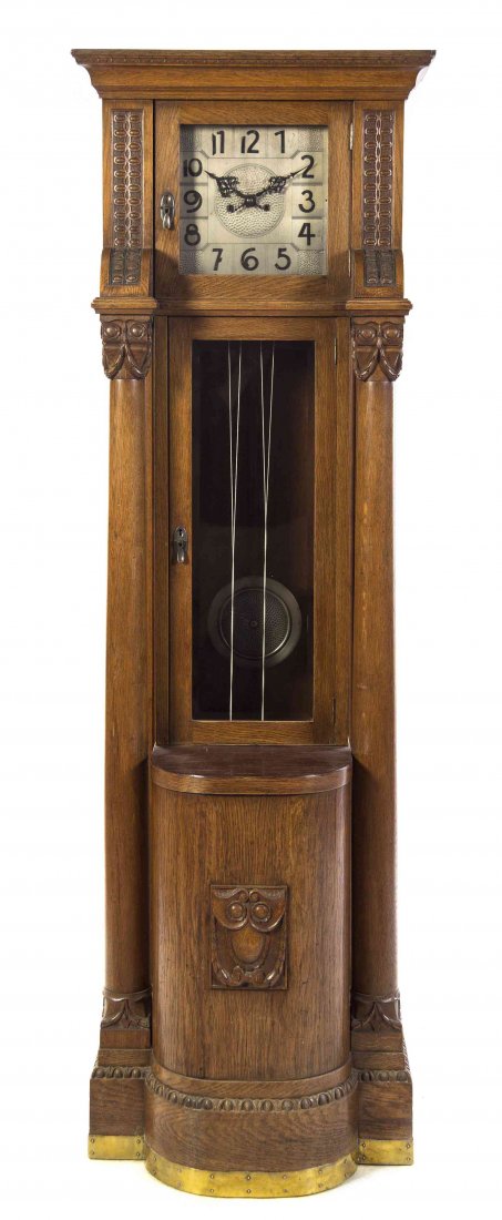 A Gustav Becker Oak Tall Case Clock, Height 74 3/4: A Gustav Becker Oak Tall Case Clock, having a hammered square face with Arabic numerals, within a carved case. Height 74 3/4 inches.