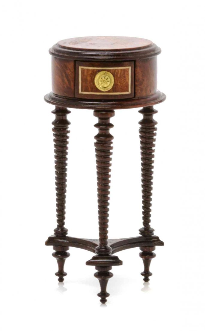 A Regency Style Burlwood Jardiniere Stand, Height 2 7/8: A Regency Style Burlwood Jardiniere Stand, GILBERT MENA, 1995, having a circular top with molded edge over a frieze drawer, raised on spiral twist supports on a tripartite base ending in ring turned f