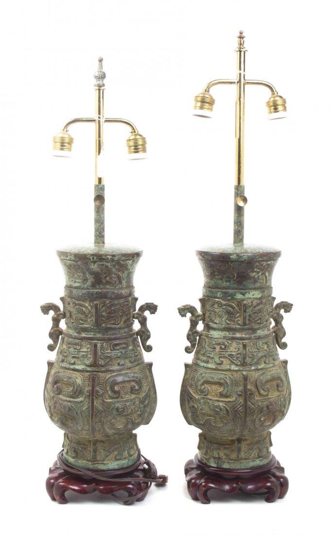 A Pair of Chinese Bronze Vessels, Height of bronze 14: A Pair of Chinese Bronze Vessels, each having tiger form handles, the bodies with relief inscription above hands of taotie masks with vertical raised flanges mounted on wood bases as two-light lamps. 