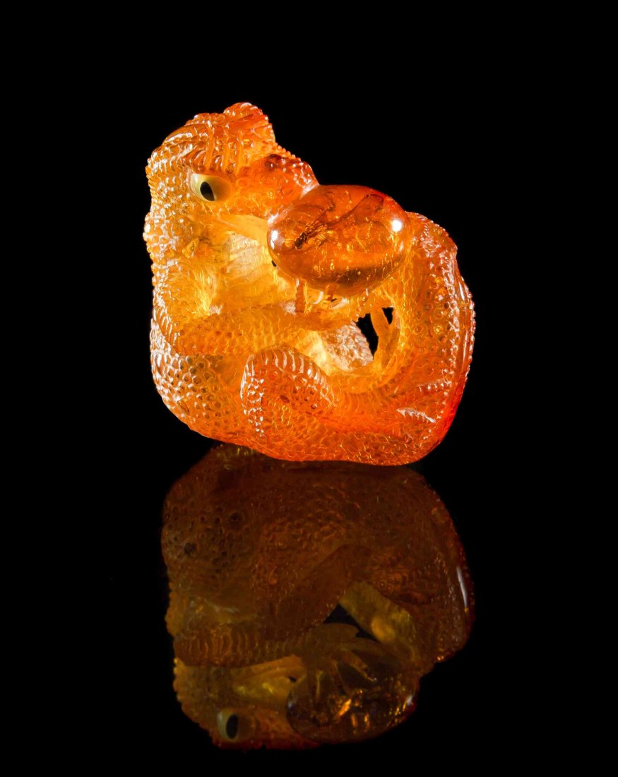 An Amber with Insect Inclusion Gecko with Egg": An Amber with Insect Inclusion "Gecko with Egg" Carving, Dominican Republic, carved from a single piece of Dominican golden amber, a naturally occurring insect inclusion within the amber was cleverly 