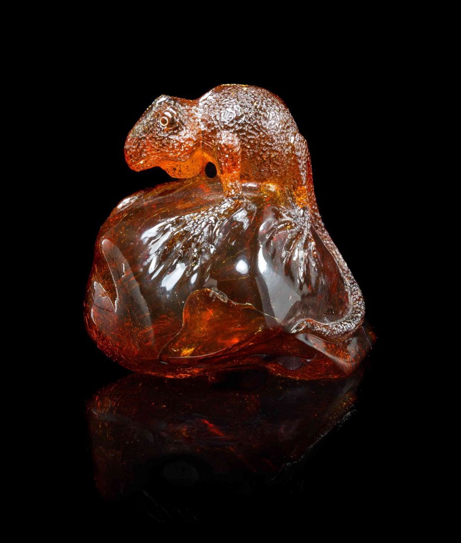 An Amber Lizard Carving,, Dominican Republic,, composed: An Amber Lizard Carving, Dominican Republic, composed of a solid carved piece of intense reddish orange amber, the intricately textured lizard perched with clutching legs and tail upon a polished and 