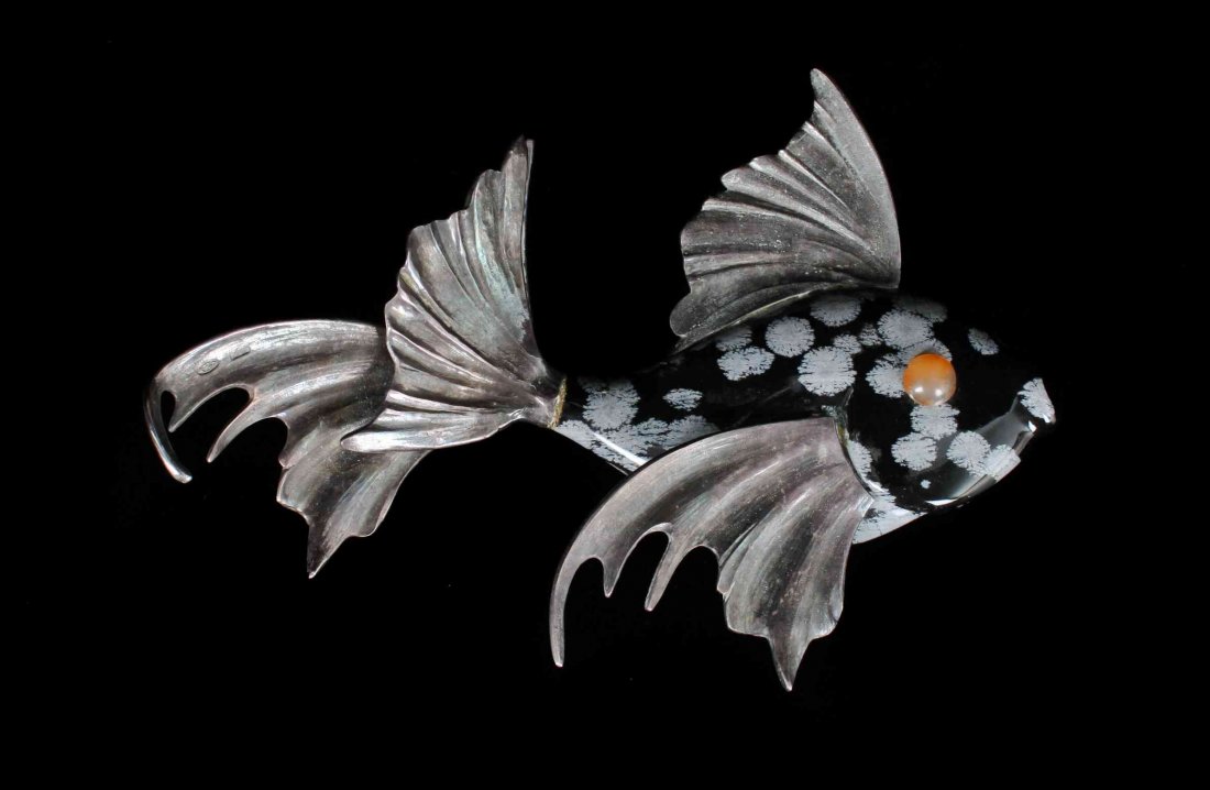 A Carved Snowflake Obsidian Fish,, , consisting of a: A Carved Snowflake Obsidian Fish, consisting of a carved snowflake obsidian body accented with fluted silver tone fins and inset orange hardstone eyes. Property from the Estate of Gerard L. Cafesjian,