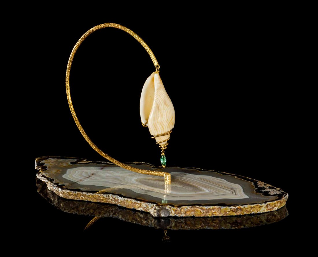 An 18 Karat Yellow Gold, Agate, Shell and Tourmaline: An 18 Karat Yellow Gold, Agate, Shell and Tourmaline Objet D'Art, Andrew Grima, consisting of a banded agate slice supporting a curved and textured gold loop supporting a wire wrapped shell and marqui