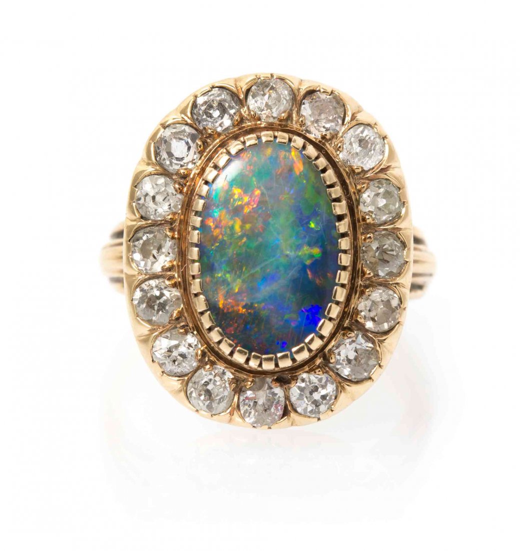 A Yellow Gold, Black Opal and Diamond Ring, 3.10 dwts.: A Yellow Gold, Black Opal and Diamond Ring, containing one oval buff top opal measuring approximately 12.80 x 8.45 mm and 16 old mine cut diamonds weighing approximately 0.96 carat total. 3.10 dwts. P