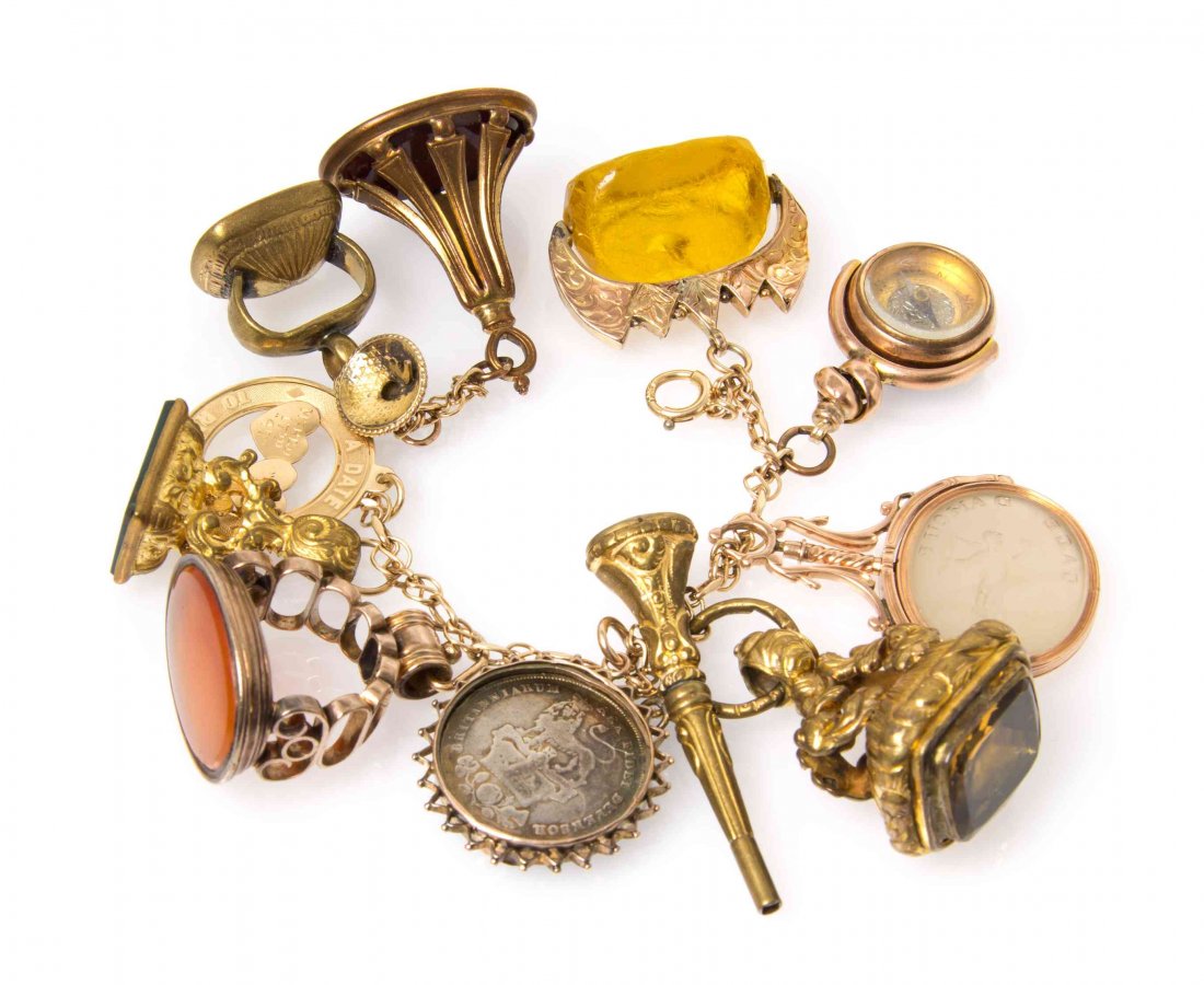 A Yellow Gold Charm Bracelet with 12 Attached Fobs and: A Yellow Gold Charm Bracelet with 12 Attached Fobs and Charms, consisting of numerous gold, goldtone and goldfilled charms and fob containing bloodstone, carnelian, quartz, coin and agate. 74.90 dwts.