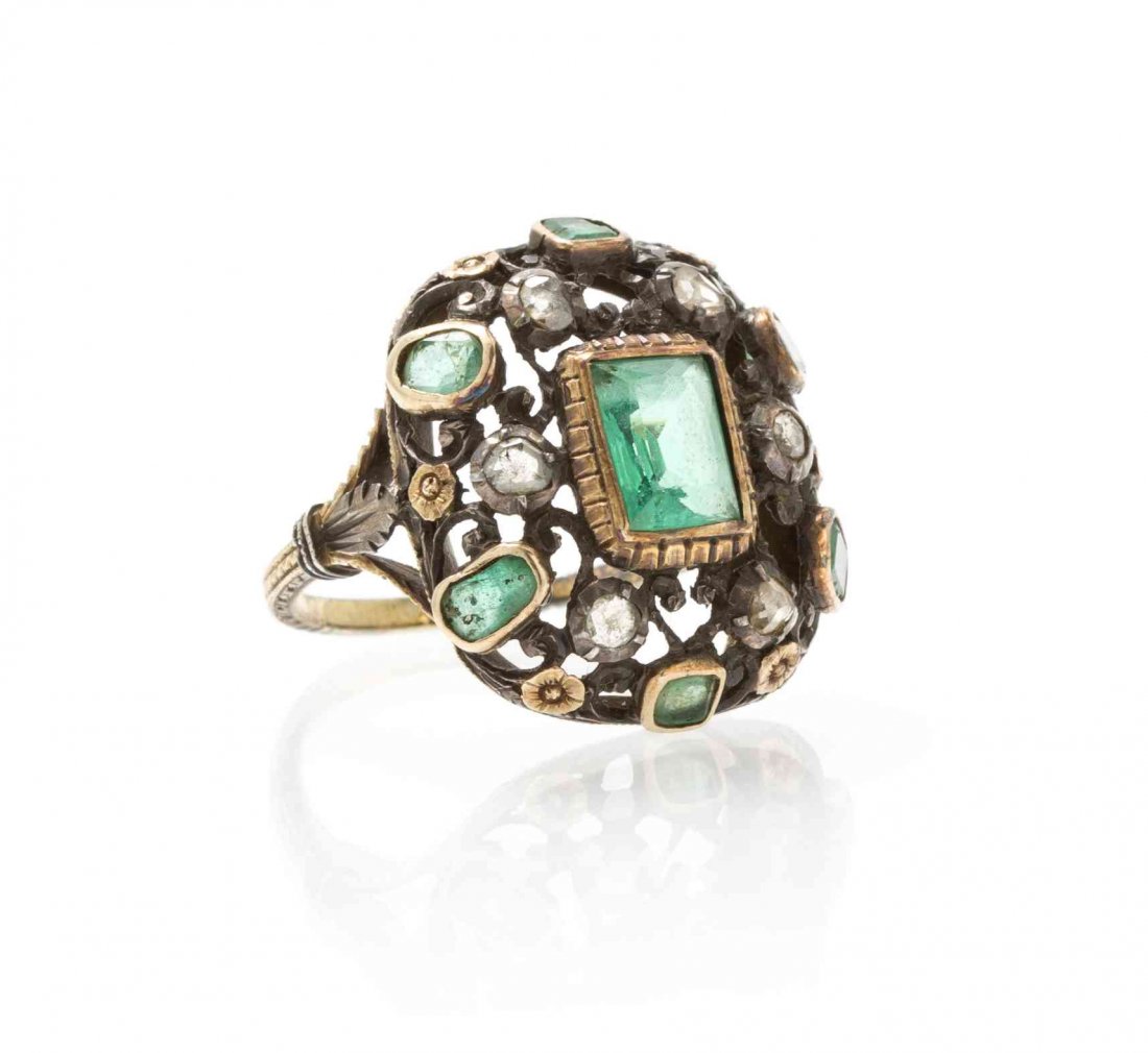 A Silver Topped Gold, Emerald and Diamond Ring, 3.30: A Silver Topped Gold, Emerald and Diamond Ring, containing one square cut emerald measuring approximately 7.37 x 4.96 x 3.80 mm, six single cut emeralds and six rose cut diamonds in a floral and scrol