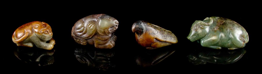 A Group of Chinese Carved Jade Animal Figures, Width of: A Group of Chinese Carved Jade Animal Figures, comprising an archaistic winged bear toggle with opaque russet skin, a recumbent lion with a wang character incised to its forehead, a recumbent ox in a 