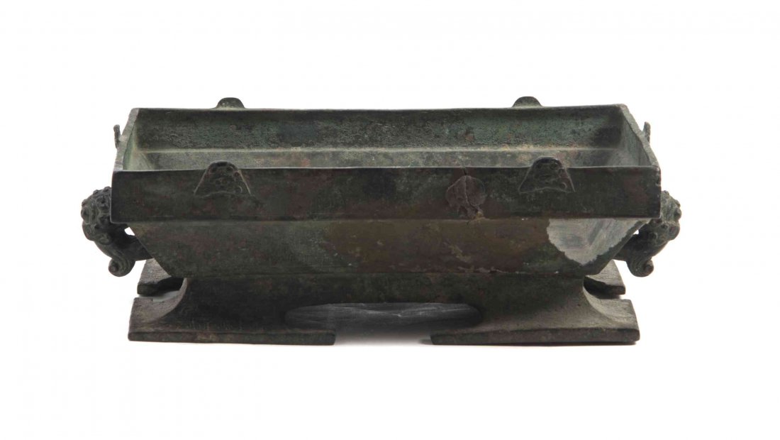 A Bronze Ritual Vessel, Width at widest 13 3/4 inches.: A Bronze Ritual Vessel, ZHOU DYNASTY (c. 1050-256 BCE) of rectangular form with beast mask handles and a splayed foot, having inscription to interior, lacking cover. Width at widest 13 3/4 inches. Pro