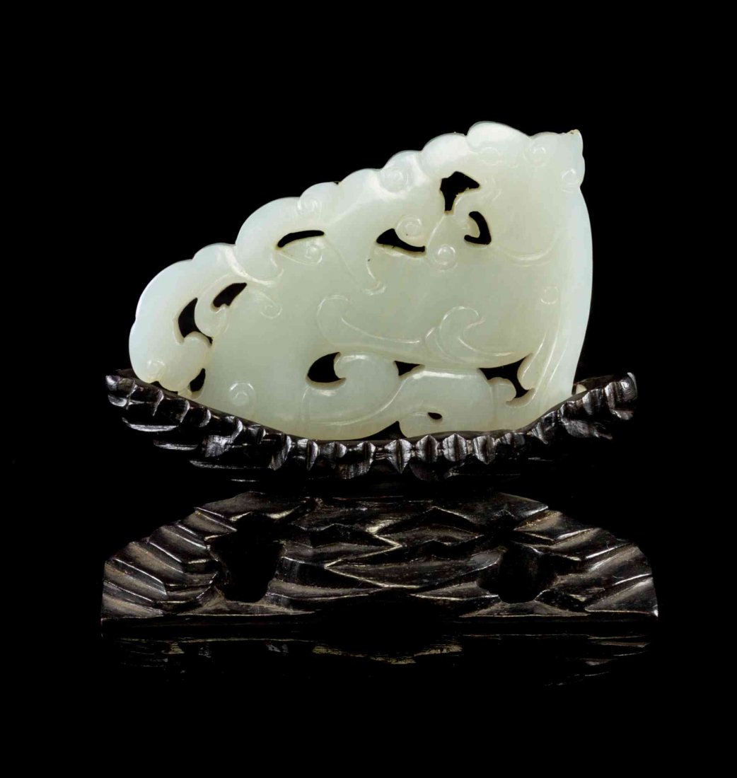 A Carved White Jade Toggle, Width 2 3/4 inches.: A Carved White Jade Toggle, depicting a chilong, with a carved wood stand. Width 2 3/4 inches. Property from the Collection of James S. Frankenberger, Downers Grove, Illinois